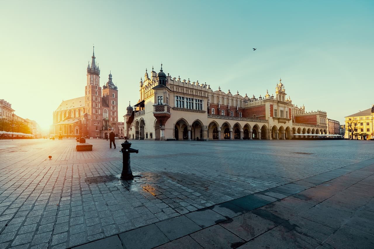 Sunlit city square with historic architecture and empty cobblestone streets.